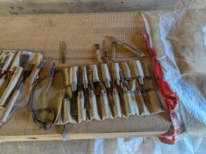 An artist's pouch holding many wood carving tools