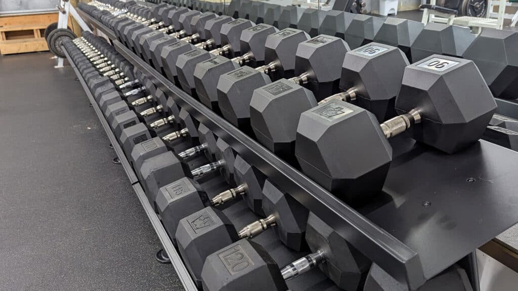 A full row of black rubber hex weights that range in weight from 1 to 120 kg.