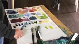 A palette or paint and hands holding a paint brush