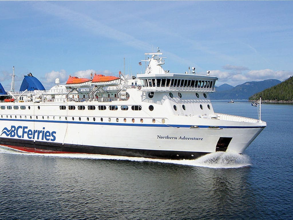 A BC Ferries ferry is sailing with mountains in the background